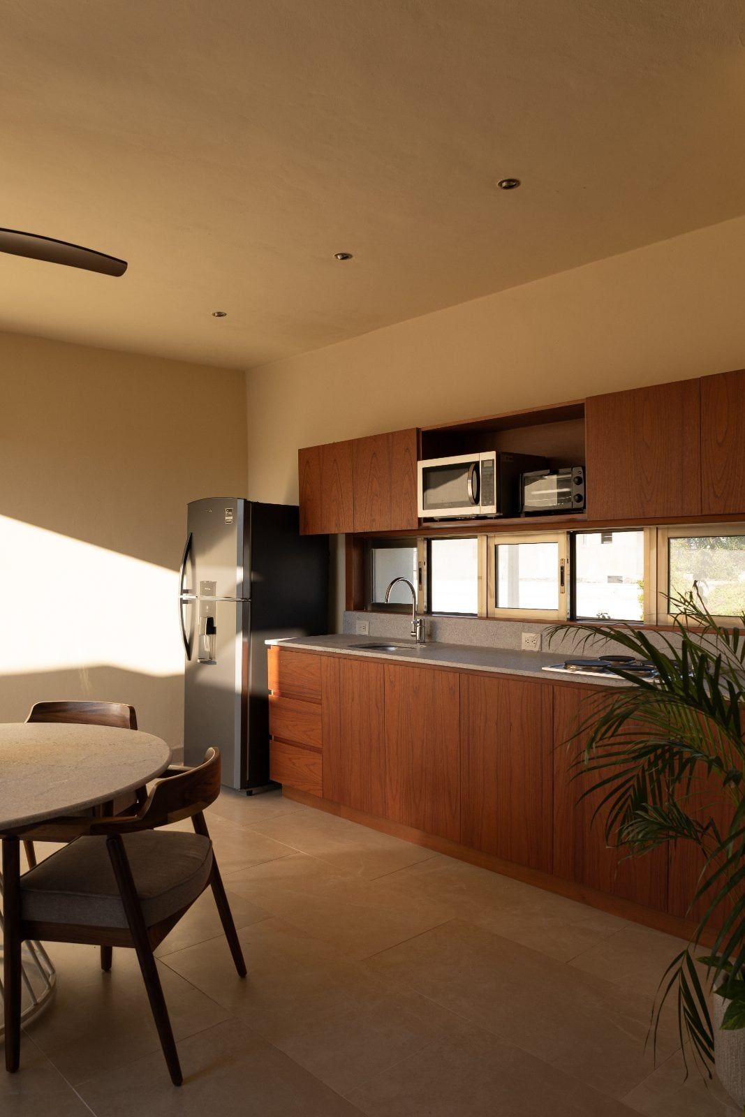 Cocina con gabinetes de madera y comedor redondo a la luz de la tarde