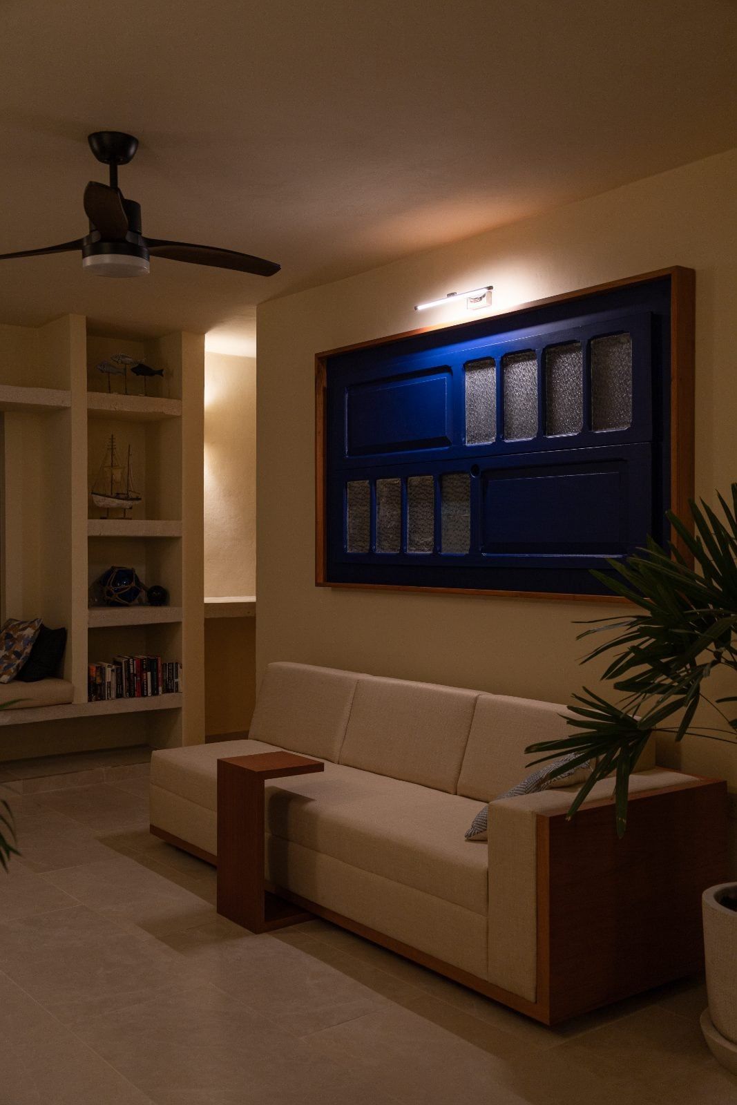 Sala con sillón, una ventana antigua enmarcada en el muro y repisas de obra